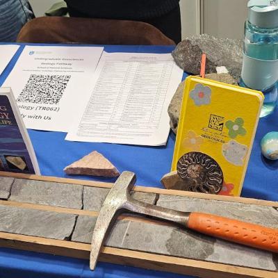 Rock specimens, hammer, filed notebook, books all laid out on stand table